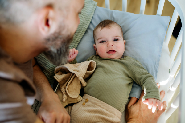 Father putting the baby to sleep, lying next to him in the crib and soothing him.