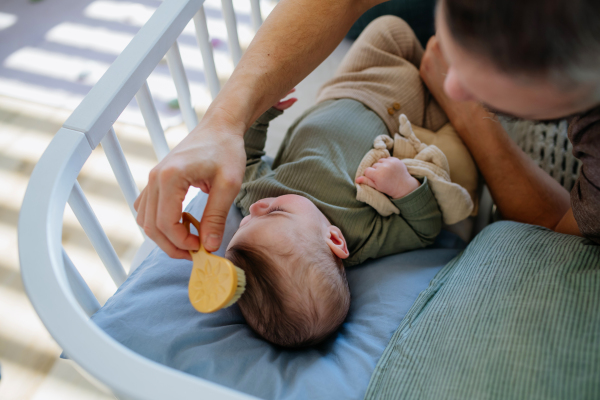 Father putting the baby to sleep, lying next to him in the crib and soothing him.