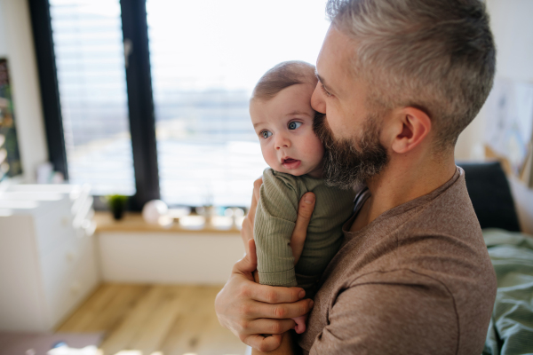 Portrait of father holding baby son in his arms.