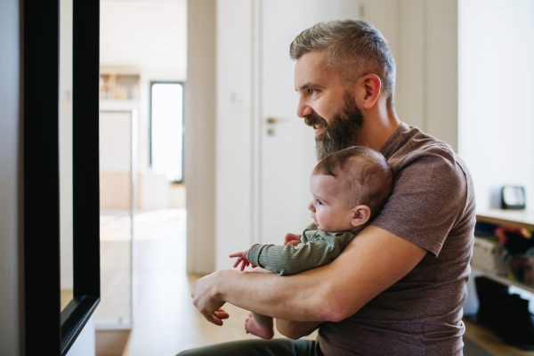 Portrait of father holding baby son in his arms and looking in the mirror.