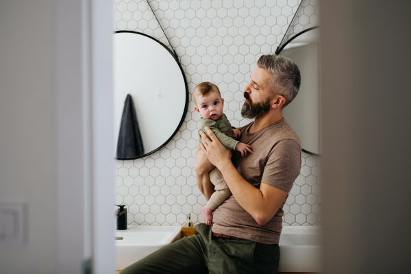 Portrait of father holding baby son in his arms.