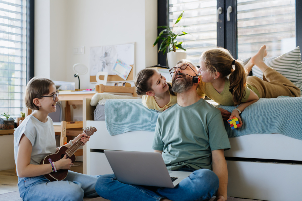 Father with three daughters trying to work from homeoffice. Girl dad concept.