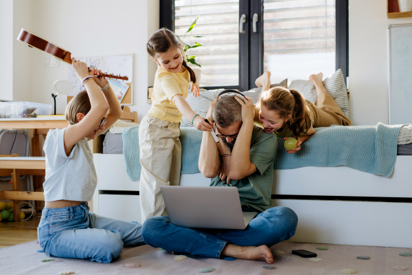 Father with three daughters trying to work from homeoffice. Girl dad concept.