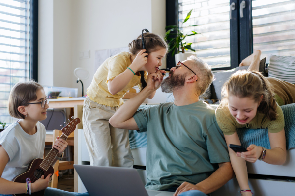 Father with three daughters trying to work from homeoffice. Girl dad concept.