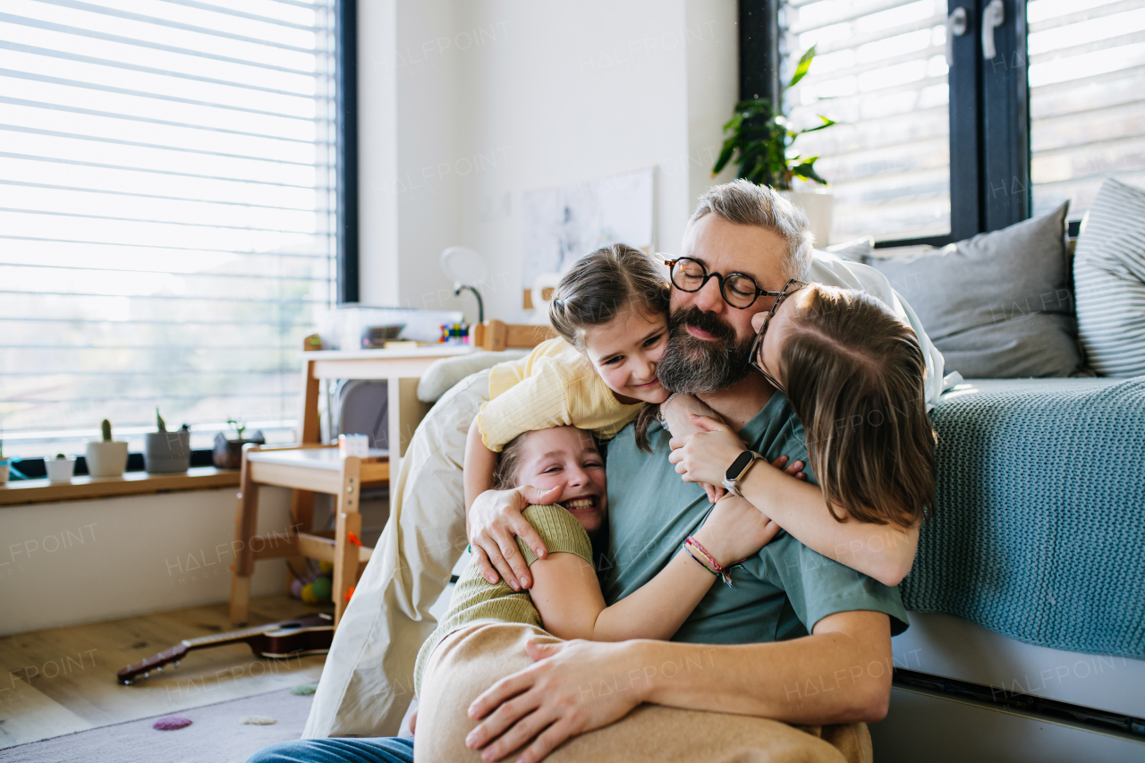 Portrait of father with three daughters at home. Girl dad concept.