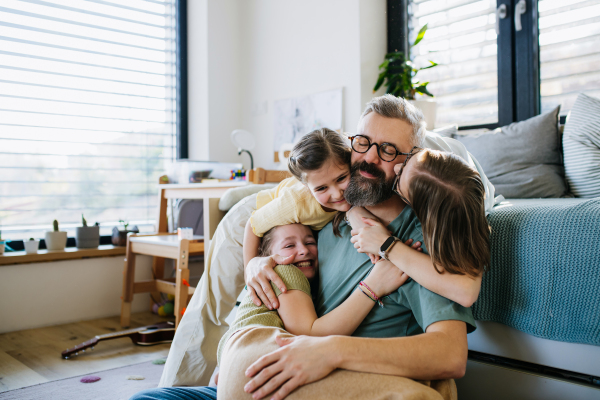 Portrait of father with three daughters at home. Girl dad concept.