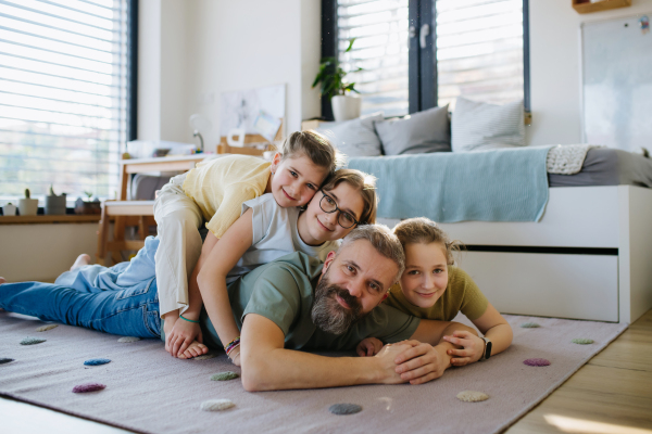 Portrait of father with three daughters at home. Girl dad concept.