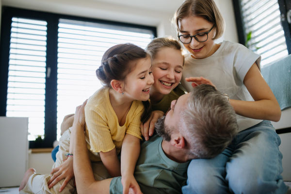 Portrait of father with three daughters at home. Girl dad concept.