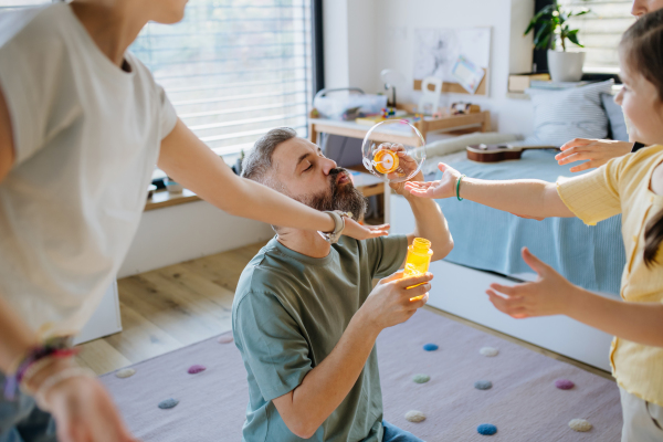 Portrait of father with three daughters blowing bubbles. Girl dad concept.
