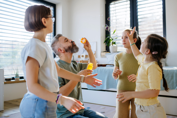 Portrait of father with three daughters blowing bubbles. Girl dad concept.