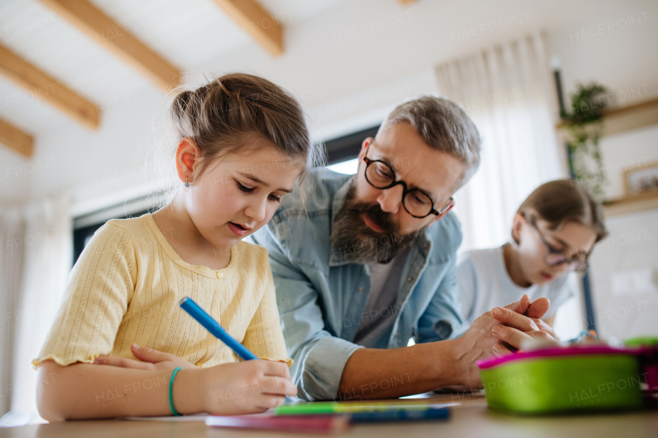 Father helping his daughters with their homework.
