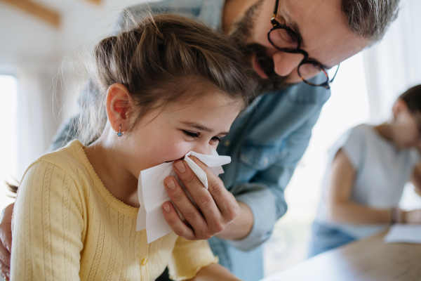 Father helping his daughter blow her congested nose.