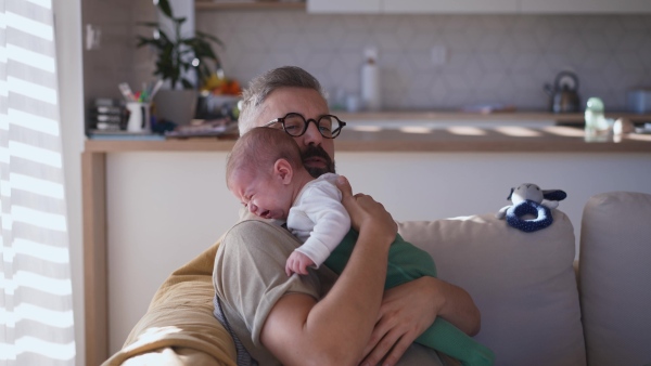 Father comforting his crying baby son, holding him in arms.