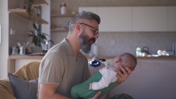 Father playing with his baby boy on a sofa.