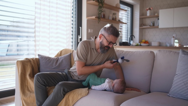 Father playing with his baby boy on a sofa.