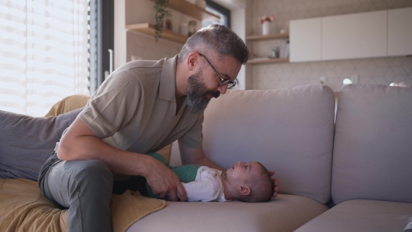 Father playing with his baby boy on a sofa.