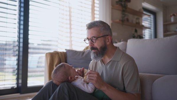 Father playing with his baby boy on a sofa.
