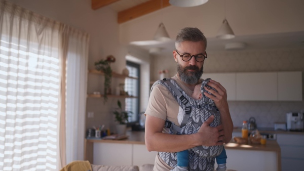 Father putting the baby to sleep, holding him in hands.