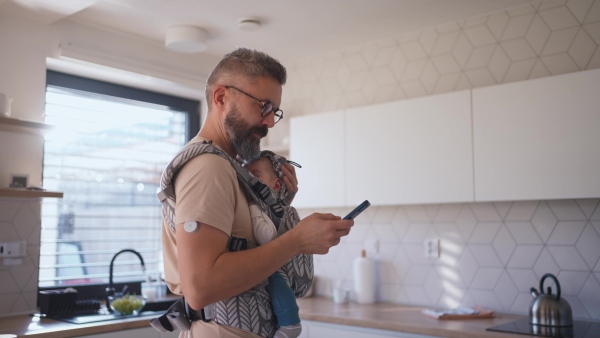 Father comforting his baby son while working, holding him in arms.