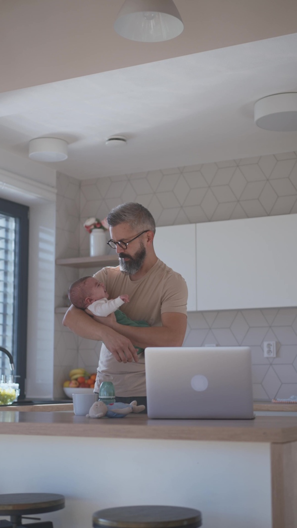 Father comforting his baby son while working, holding him in arms.