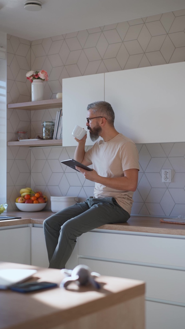 Mature man working on his tablet while having a morning coffee.