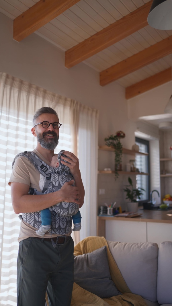 Father putting the baby to sleep, holding him in hands.