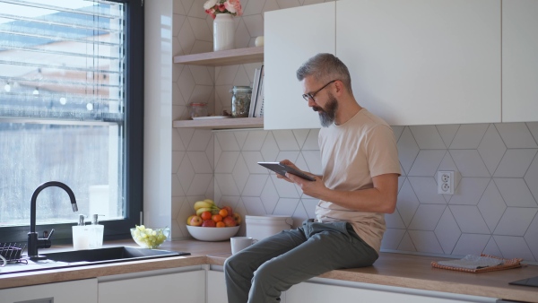 Mature man working on his tablet while having a morning coffee.