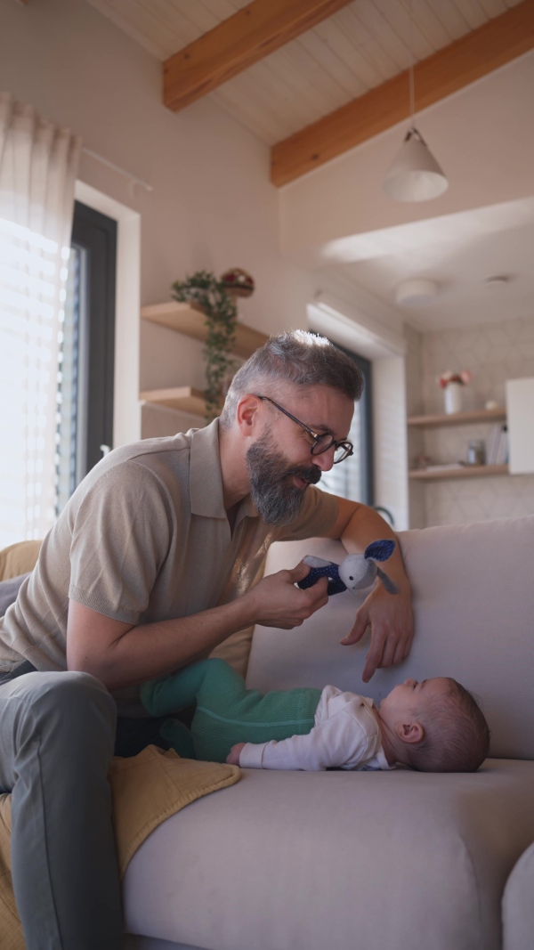 Father playing with his baby boy on a sofa.