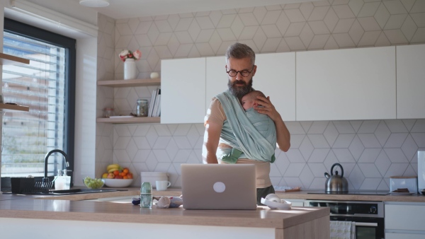 Father comforting his baby son while working, holding him in arms.