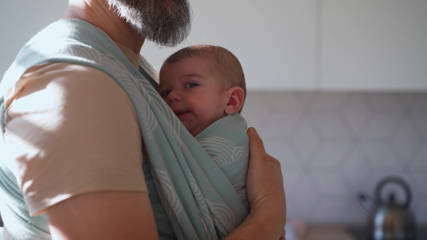 Father comforting his crying baby son, holding him in arms.