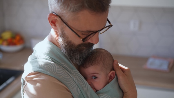 Father comforting his crying baby son, holding him in arms.