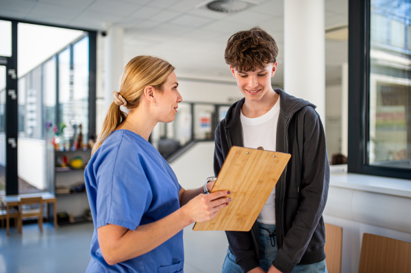 Doctor walking with teenage patient after successful checkup or medical procedure in hospital hallway.