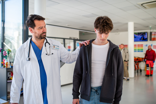 Compassionate doctor comforting young patient during hospital visit in doctors office.