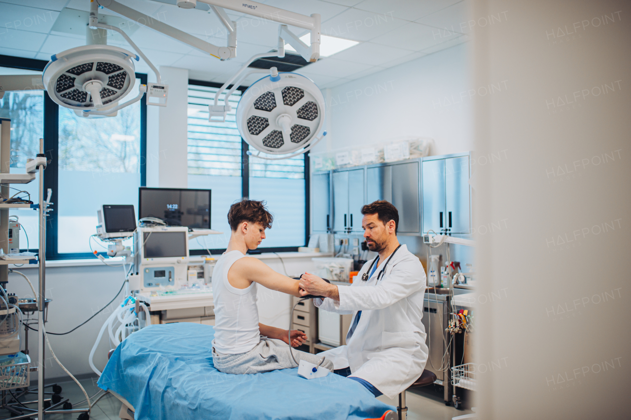 Teen boy undergoing medical checkup with smiling doctor in hospital room.