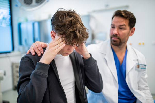 Teenager confiding in doctor about personal and health problems. Mental health evaluation for depressed teen boy.