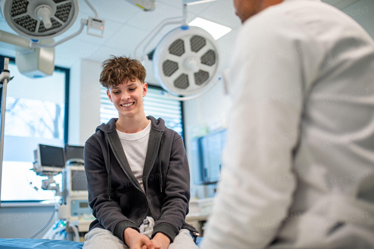Teenage boy smiling during supportive medical consultation after receiving positive health news.