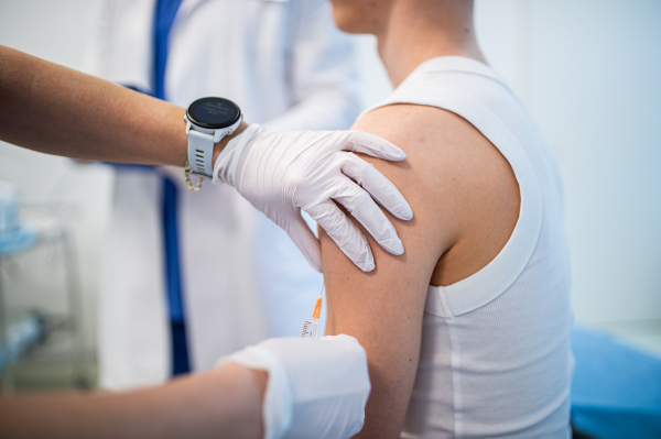 Teenage boy receiving vaccination during routine health checkup in clinic.