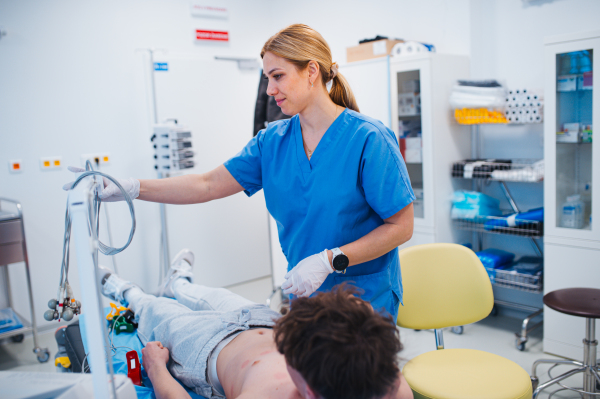 Nurse removing EKG electrodes after heart test on teenage patient, medical setting.