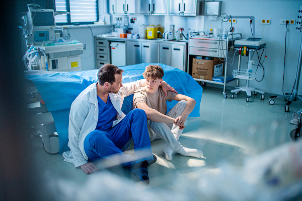 Teenager confiding in doctor about personal and health problems. Mental health evaluation for depressed teen boy.