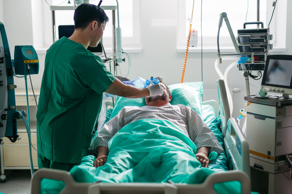 Doctor providing manual oxygen ventilation to unconscious patient in hospital