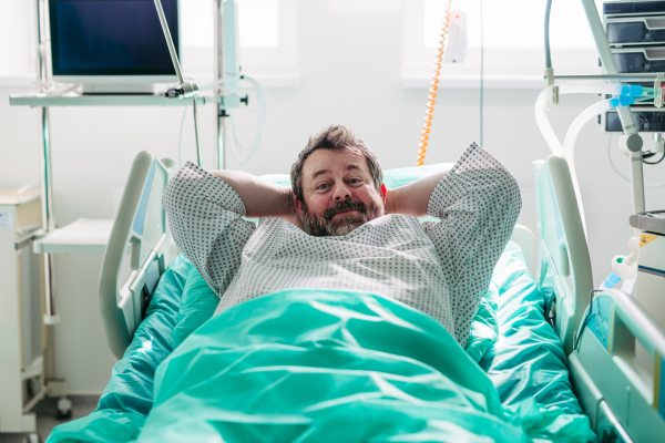 Patient resting in hospital bed with hands behind head.