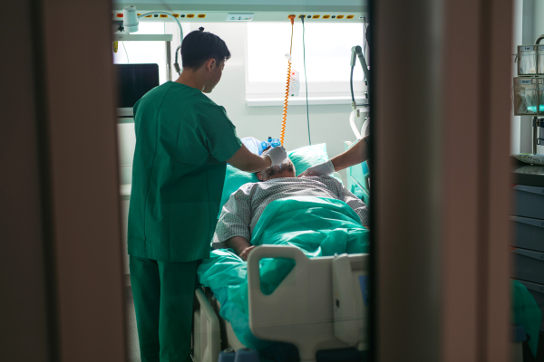 Doctor providing manual oxygen ventilation to unconscious patient in hospital