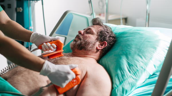 Emergency defibrillation on unconscious male patient in hospital.