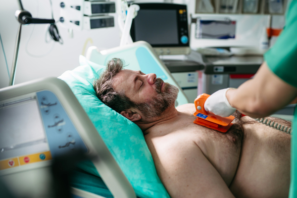 Emergency defibrillation on unconscious male patient in hospital.