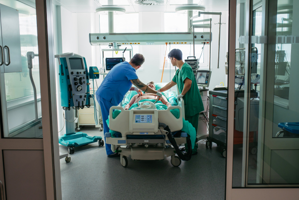 Medical team taking care of unconscious patient in hospital bed. Intensive care unit.