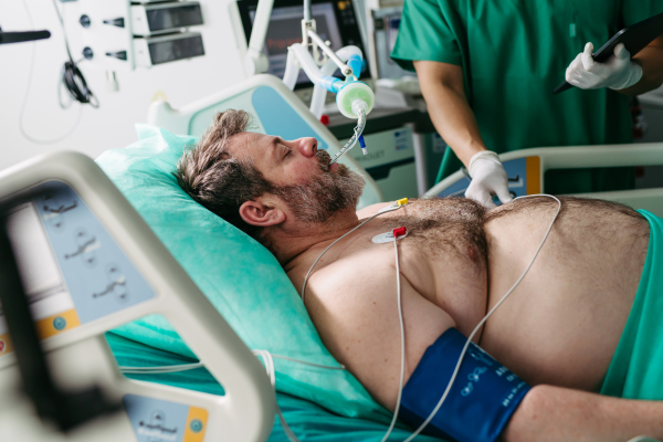 Doctor taking care of unconscious patient in hospital bed. Intensive care unit.