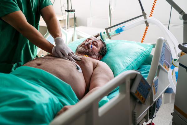 Emergency chest compressions performed on unconscious man by doctor.