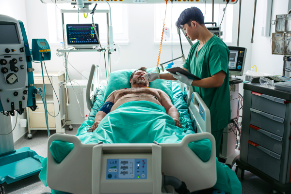 Doctor taking care of unconscious patient in hospital bed. Intensive care unit.