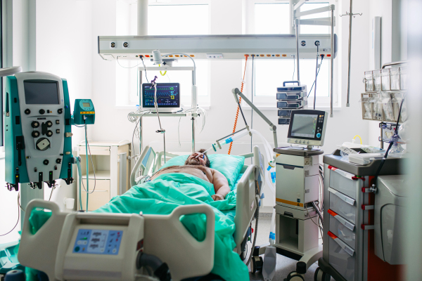 Intubated male patient lying unconscious in intensive care unit