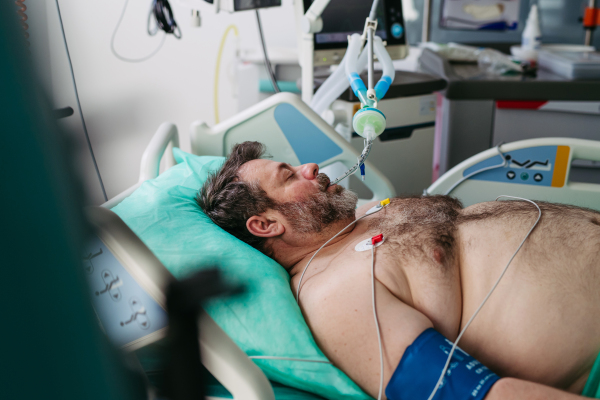 Intubated male patient lying unconscious in intensive care unit